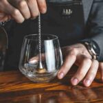 Bartender Using Muddler Tip Twisted Stem Mixing Spoon for Stirring and Light Muddling in Professional Bar
