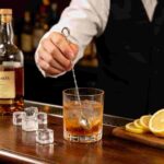 Bartender Using Ring Top Beaded Stem Swizzle Spoon for Stirring Craft Cocktails in Luxury Bar