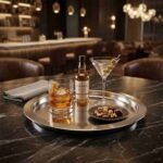 Sleek Round Stainless Steel Serving Tray Used for Serving Cocktails and Appetizers in Luxury Bar Setting
