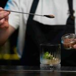 Bartender Using Sleek Straight Stem Mixing Spoon for Stirring Martinis in Luxury Bar