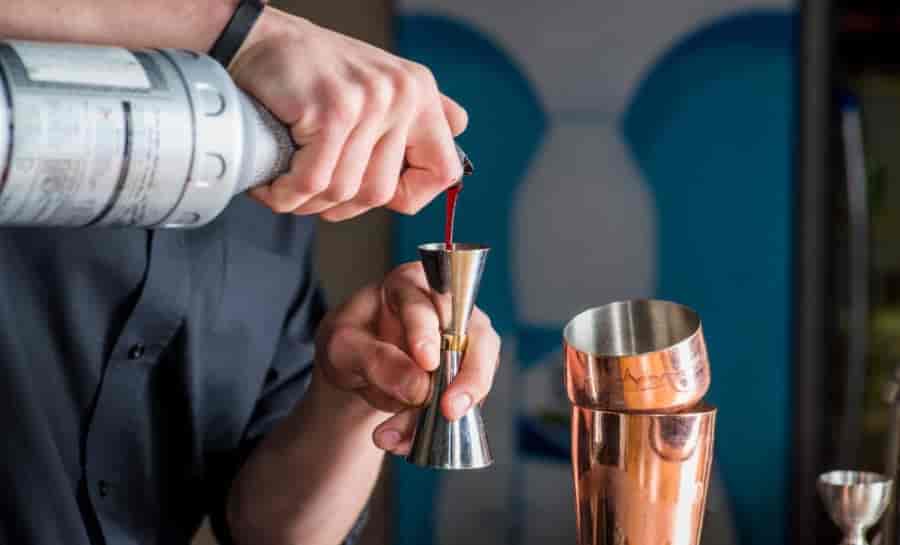 double jigger grip technique bartender holding stainless steel jigger between fingers correct hand position