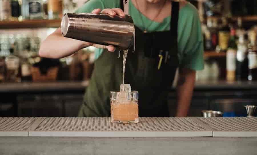 Cocktail Shaker Sizes & Capacity Guide: How to Choose the Right Size 4 professional bartender shaking stainless steel cocktail shaker two hands vigorous technique bar